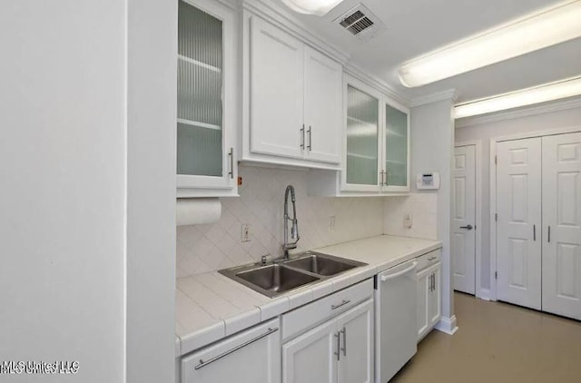 kitchen featuring white dishwasher, sink, white cabinets, and tasteful backsplash