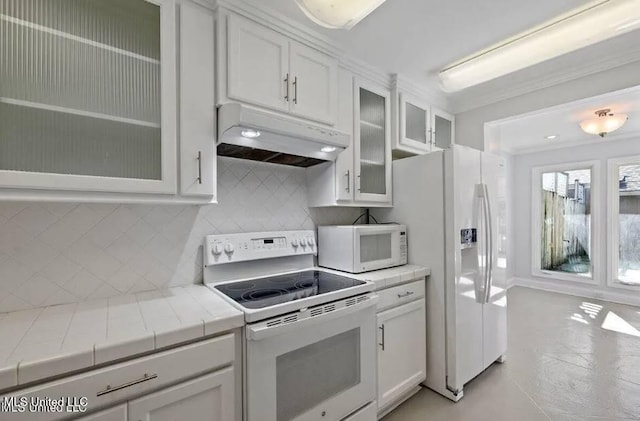 kitchen featuring white appliances, white cabinets, backsplash, light tile patterned floors, and crown molding