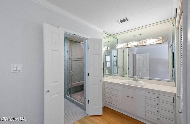 bathroom featuring crown molding, a shower with shower door, hardwood / wood-style floors, and vanity