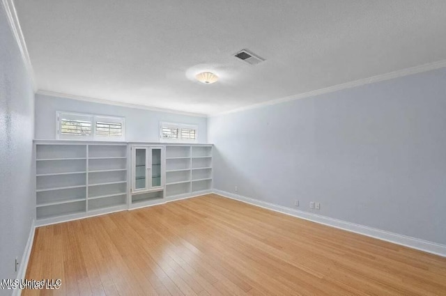 spare room featuring a textured ceiling, crown molding, and light wood-type flooring