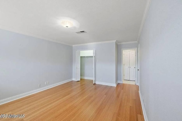 unfurnished bedroom with a closet, ornamental molding, and light wood-type flooring