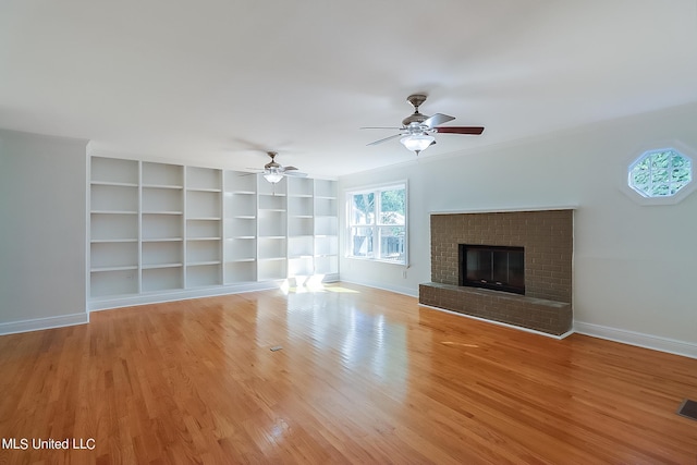 unfurnished living room with light hardwood / wood-style flooring, built in shelves, a fireplace, and ceiling fan