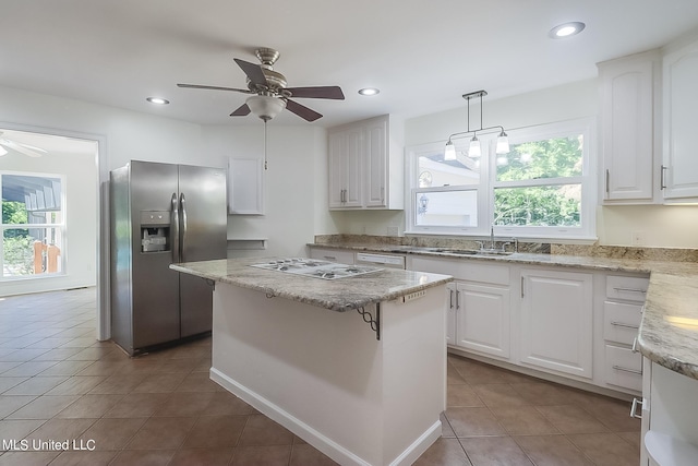 kitchen with white appliances, decorative light fixtures, white cabinets, and a kitchen island