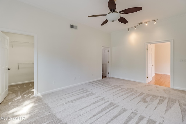 interior space with a spacious closet, light colored carpet, ceiling fan, and a closet