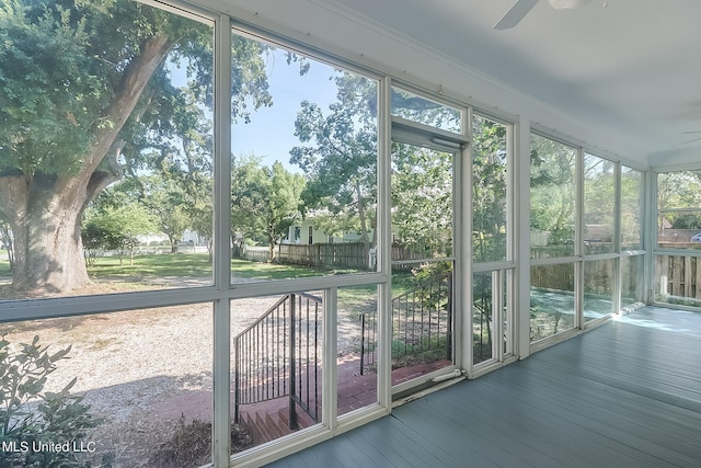 unfurnished sunroom featuring ceiling fan and plenty of natural light