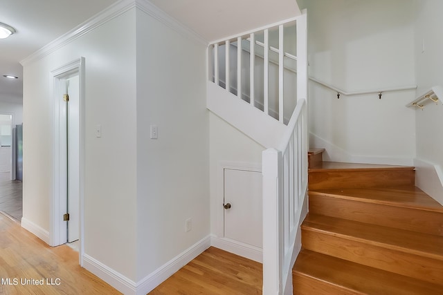 stairway with ornamental molding and hardwood / wood-style floors