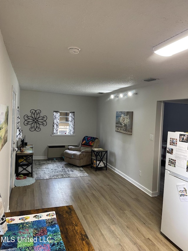 living area featuring a textured ceiling, baseboards, and wood finished floors