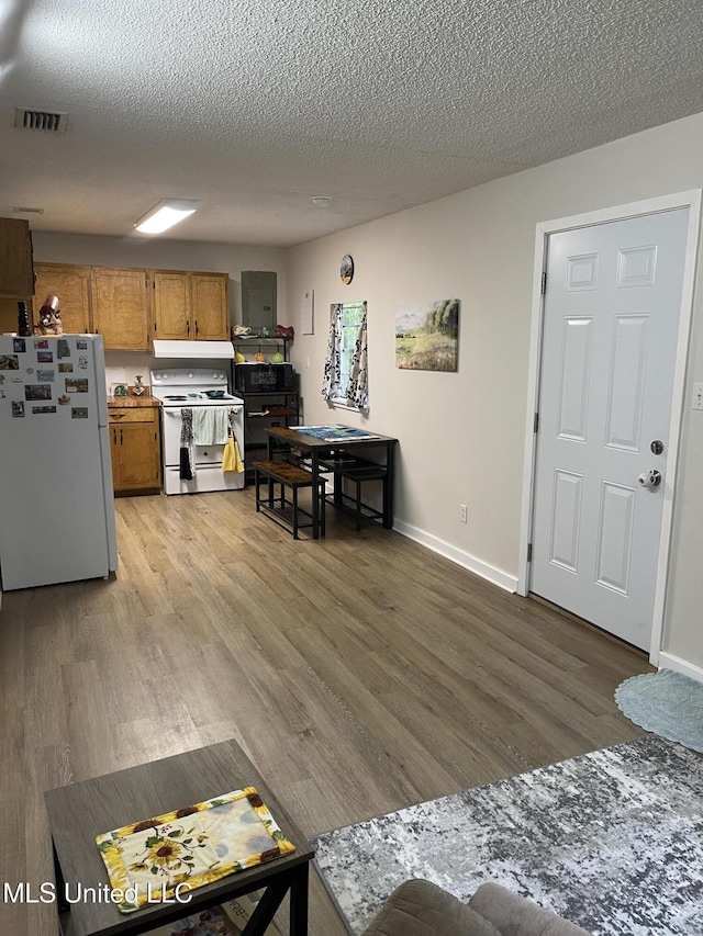 kitchen with brown cabinets, visible vents, baseboards, white appliances, and light wood-style floors