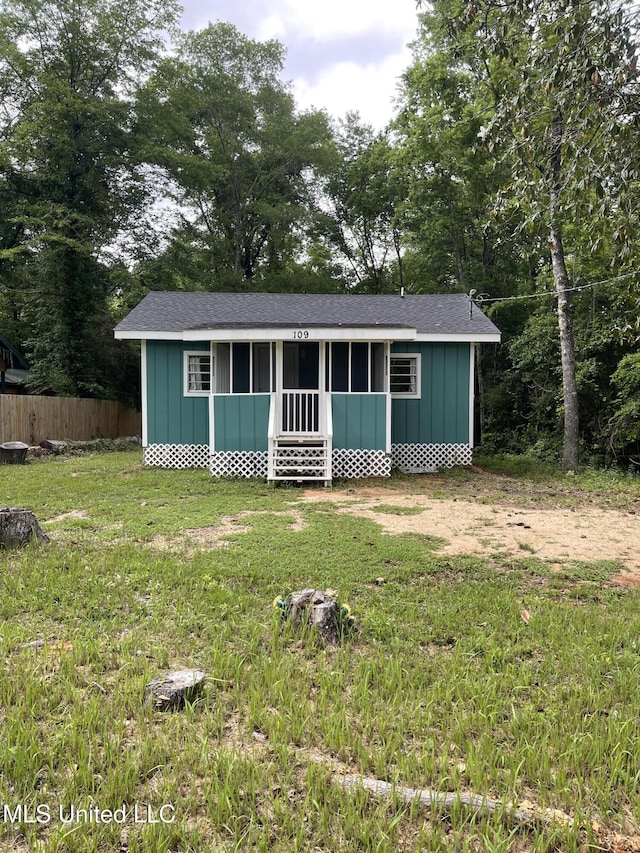 view of front of house featuring board and batten siding, a shingled roof, a front lawn, and fence