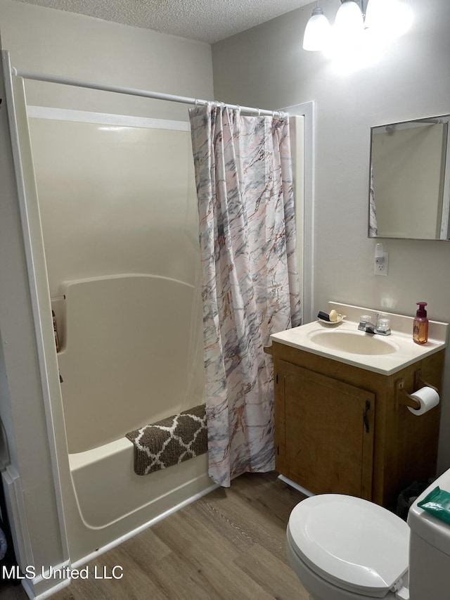 full bath featuring shower / bath combination with curtain, toilet, wood finished floors, a textured ceiling, and vanity