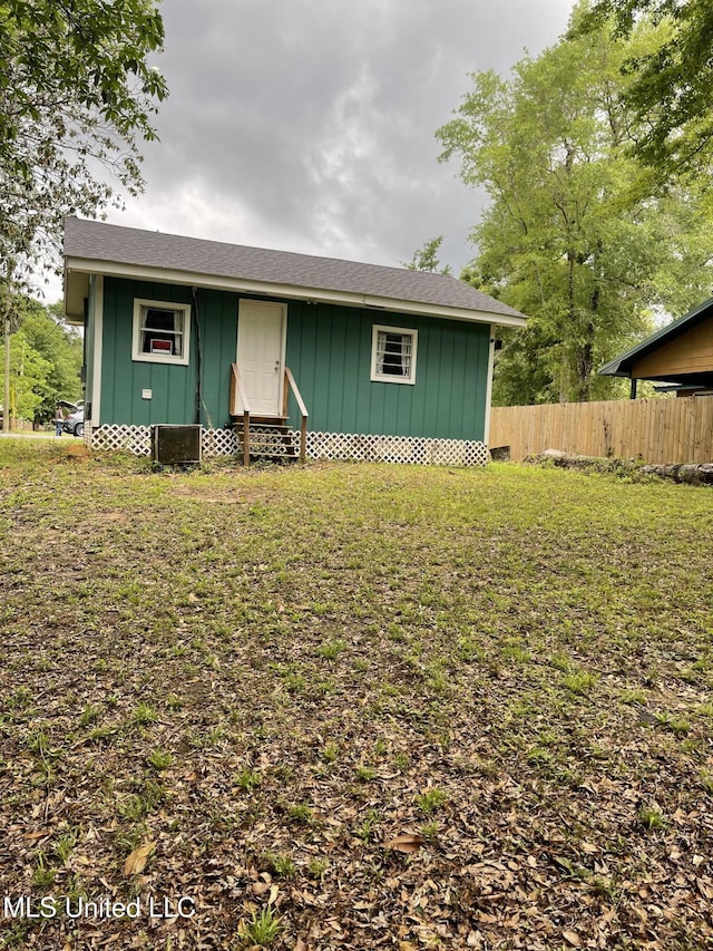 view of front of property with board and batten siding, fence, central air condition unit, entry steps, and a front lawn