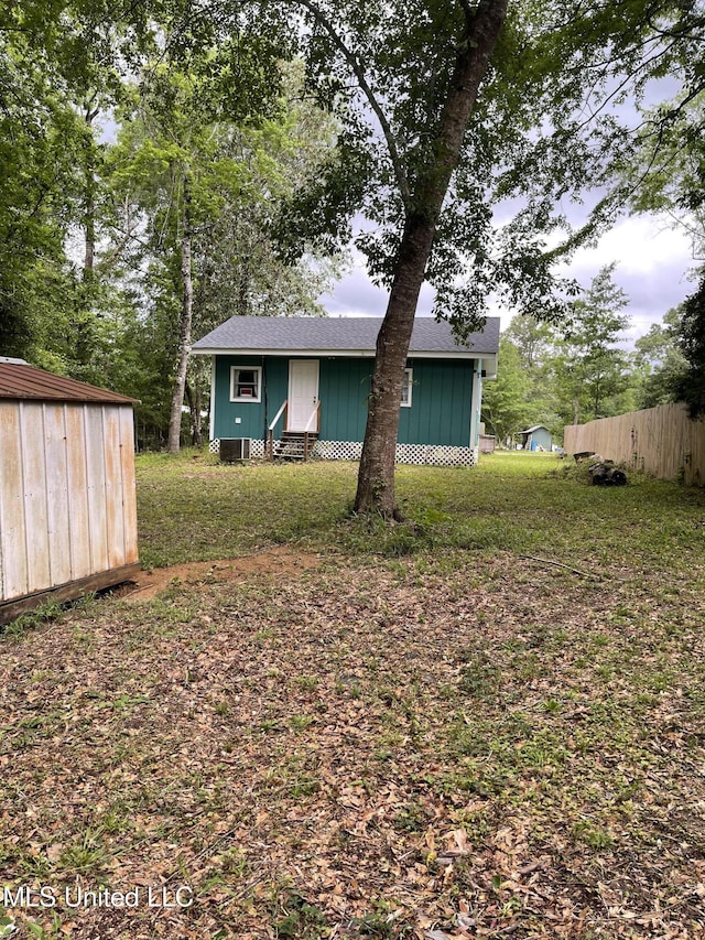 exterior space with roof with shingles, a storage shed, and an outdoor structure