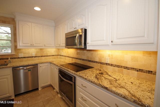 kitchen with light stone counters, ornamental molding, backsplash, white cabinetry, and appliances with stainless steel finishes