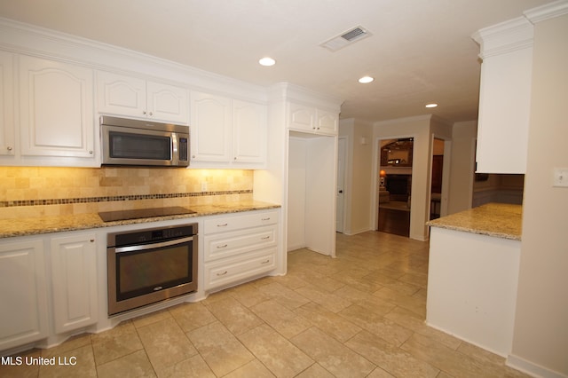 kitchen with tasteful backsplash, light stone counters, ornamental molding, stainless steel appliances, and white cabinets