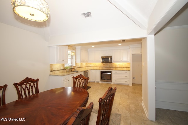 dining space featuring vaulted ceiling, sink, and crown molding