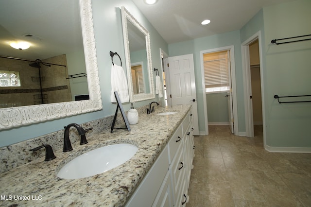 bathroom featuring tile patterned flooring, tiled shower, and vanity