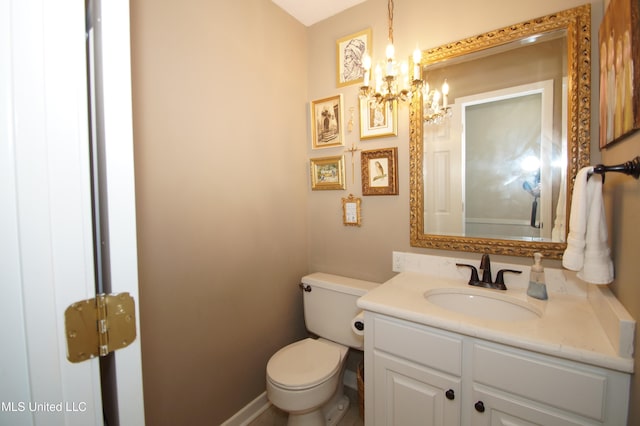 bathroom with a notable chandelier, toilet, and vanity