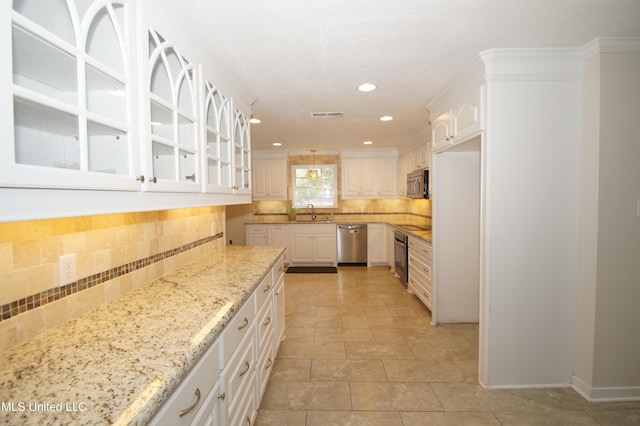 kitchen with white cabinetry, appliances with stainless steel finishes, tasteful backsplash, and light stone counters