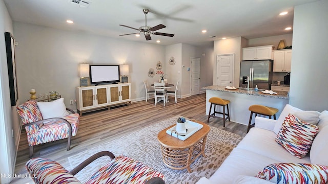 living area featuring ceiling fan, light wood-style floors, recessed lighting, and baseboards