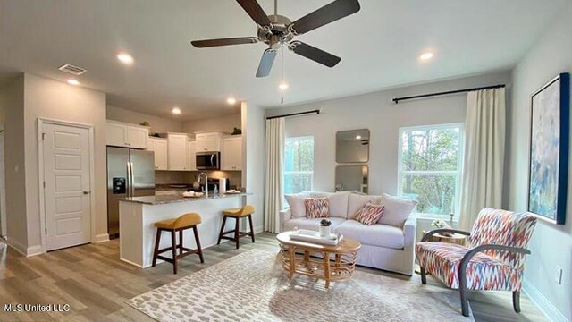 living area with a ceiling fan, light wood finished floors, baseboards, and recessed lighting