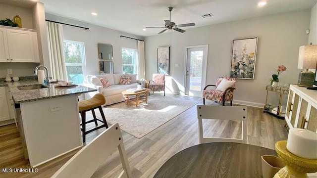 living room with wood finished floors, a ceiling fan, recessed lighting, and baseboards