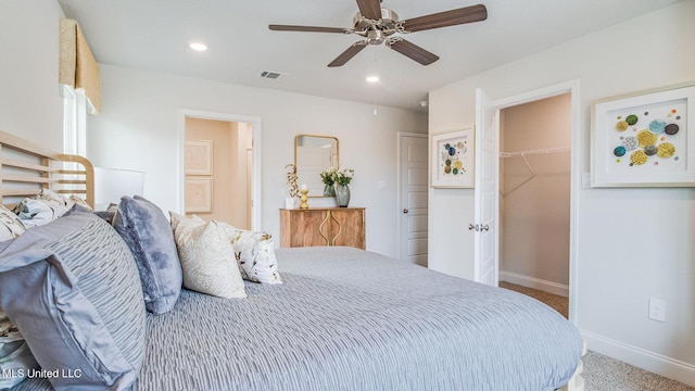 bedroom featuring a walk in closet, baseboards, carpet flooring, a closet, and a ceiling fan