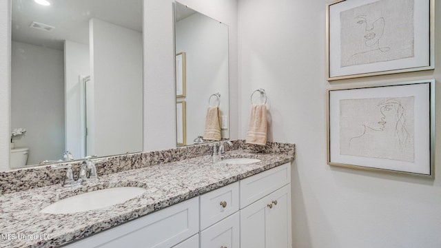 bathroom with double vanity and toilet