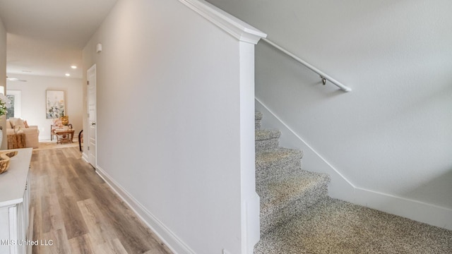 stairs with wood finished floors, recessed lighting, and baseboards