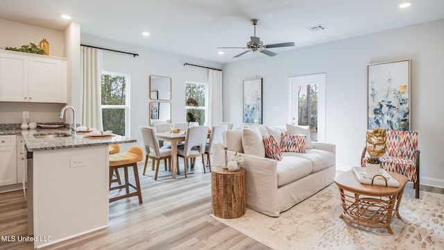 living room featuring light wood-style flooring, a ceiling fan, and recessed lighting