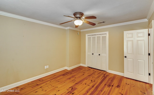 unfurnished bedroom with hardwood / wood-style floors, ceiling fan, ornamental molding, and a closet