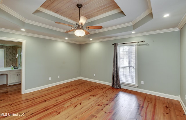 empty room featuring a raised ceiling, ceiling fan, light hardwood / wood-style flooring, and ornamental molding