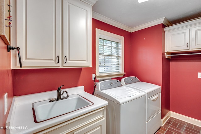 laundry area featuring crown molding, washer and clothes dryer, cabinets, and sink