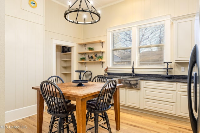 dining space with crown molding, light hardwood / wood-style flooring, wooden walls, and sink