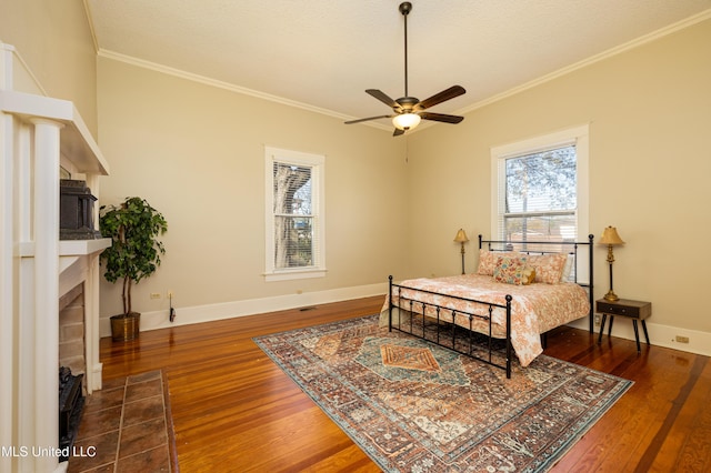 bedroom with a textured ceiling, ceiling fan, crown molding, wood-type flooring, and a fireplace