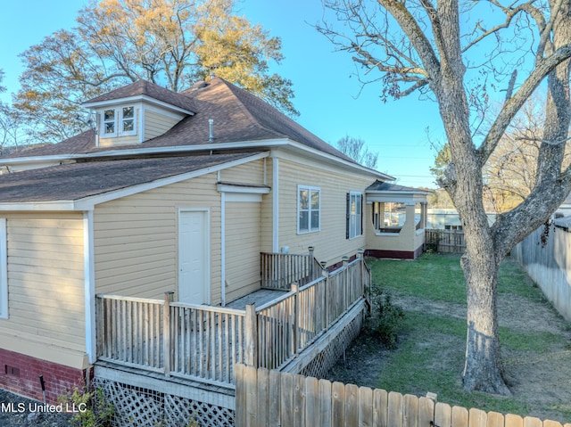 back of property with a lawn and a deck