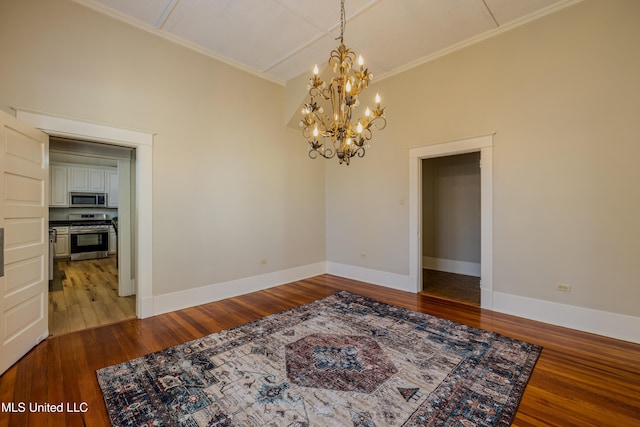 empty room with crown molding, hardwood / wood-style floors, and a notable chandelier