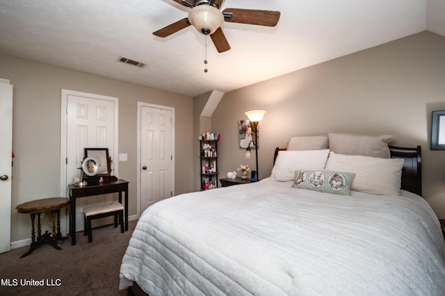 bedroom featuring ceiling fan, lofted ceiling, dark carpet, and two closets