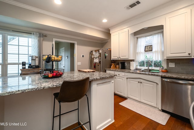 kitchen with stainless steel appliances, white cabinetry, sink, and light stone counters