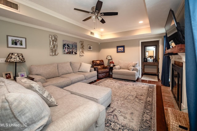 living room featuring crown molding, hardwood / wood-style floors, a tray ceiling, and ceiling fan