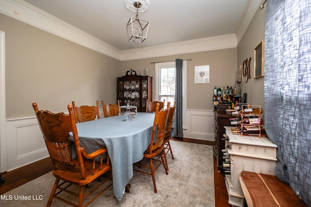 dining area with hardwood / wood-style flooring, crown molding, and a notable chandelier