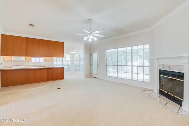 696 Aukai Pl, Diamondhead, MS 39525 - unfurnished living room with crown molding, a tile fireplace, a sink, a ceiling fan, and light colored carpet
