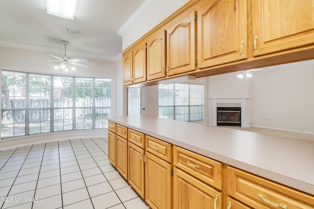 696 Aukai Pl, Diamondhead, MS 39525 - kitchen with ceiling fan, crown molding, light countertops, a tiled fireplace, and light tile patterned floors