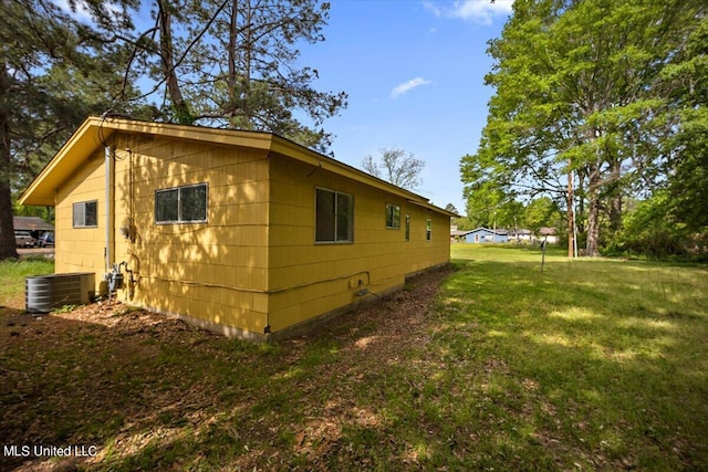 view of side of home with central AC and a lawn