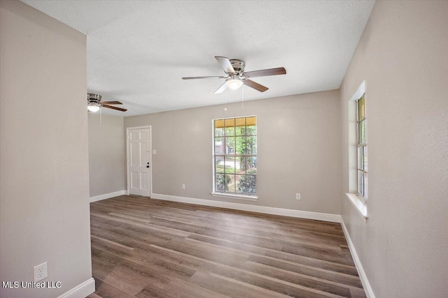 unfurnished room with a textured ceiling, dark wood-type flooring, and ceiling fan