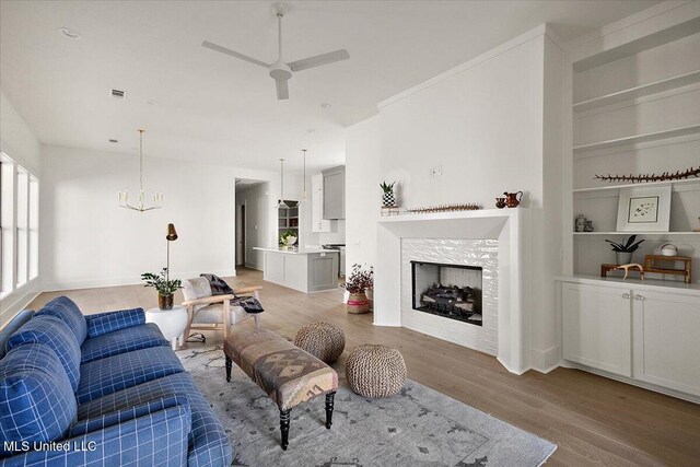113 Water St, Madison, MS 39110 - living room with a chandelier, ceiling fan, light wood-style floors, a fireplace, and built in features