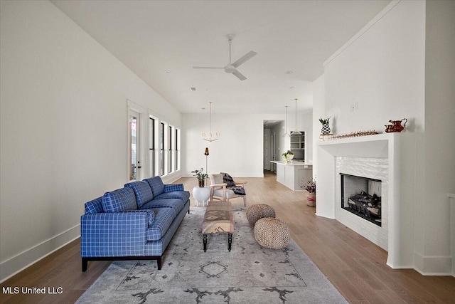 113 Water St, Madison, MS 39110 - living room with wood finished floors, baseboards, a ceiling fan, a fireplace, and a chandelier