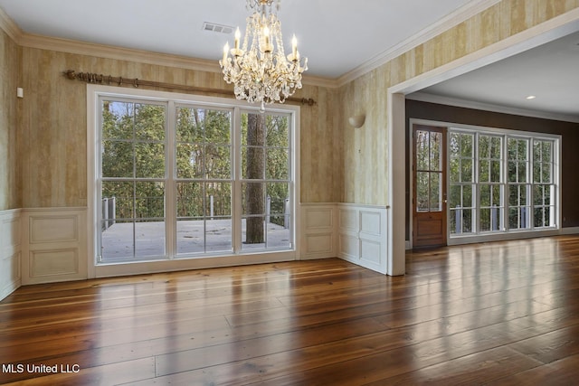 unfurnished dining area featuring an inviting chandelier, crown molding, and dark wood-type flooring