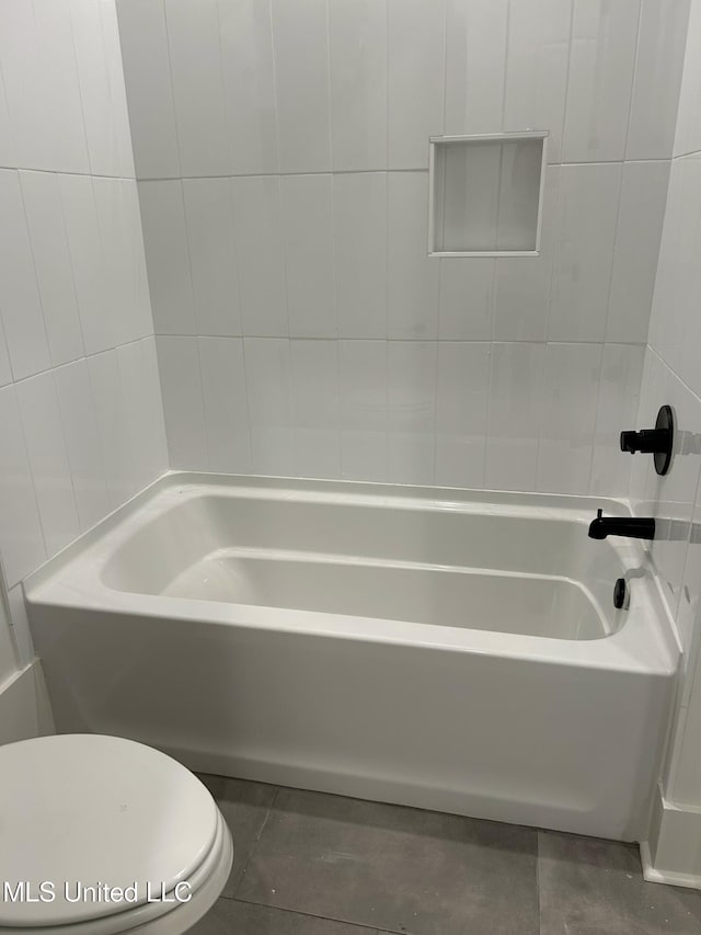 bathroom featuring washtub / shower combination, tile patterned floors, and toilet