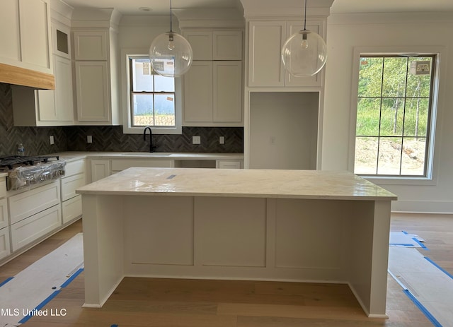 kitchen featuring light stone counters, sink, and pendant lighting