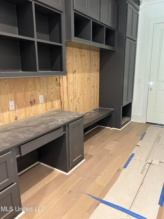 mudroom with light hardwood / wood-style flooring and wooden walls